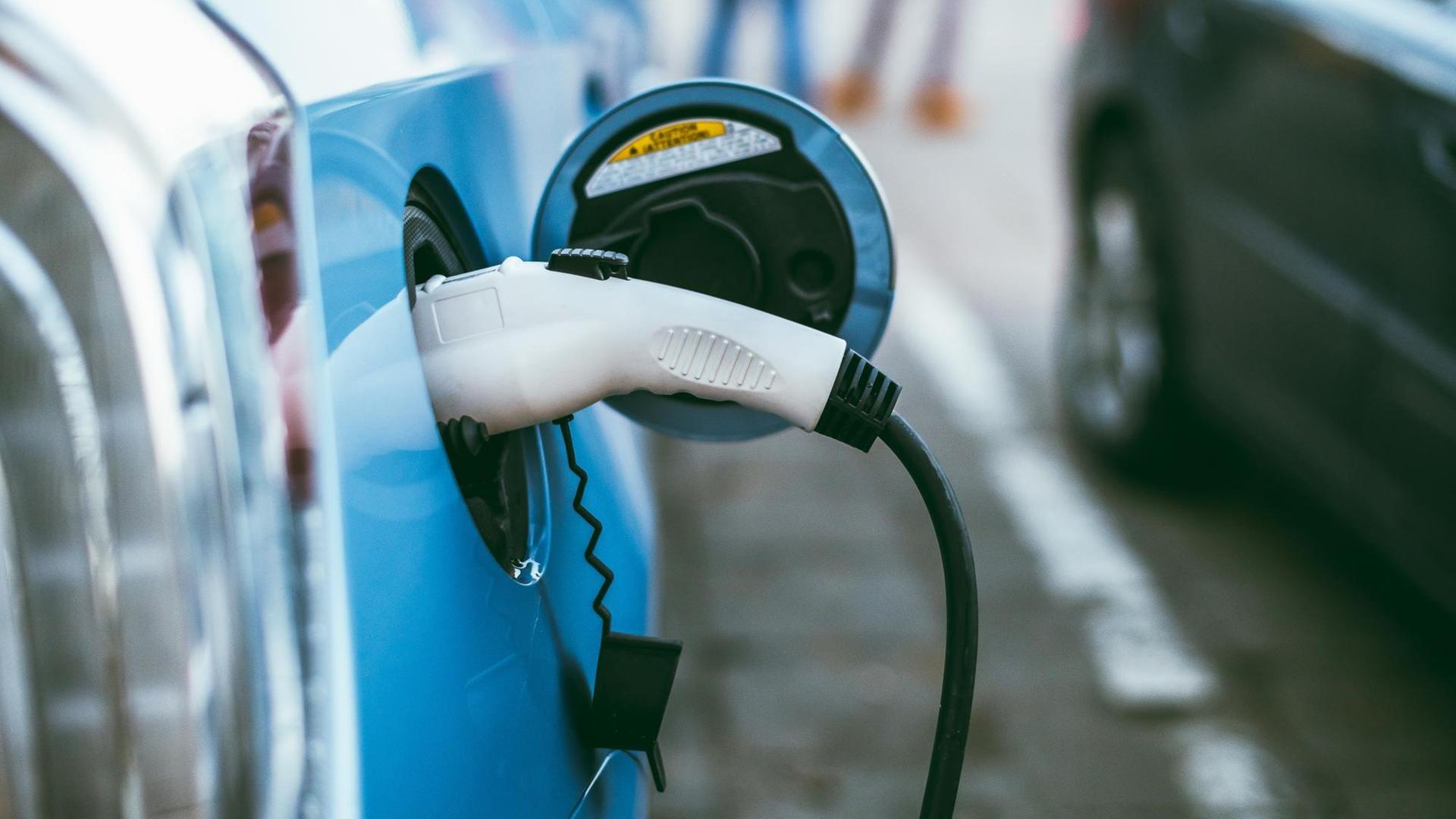 Ein blaues Elektroauto lädt an einer Ladesäule. Ein blaues Elektroauto lädt an einer Ladesäule.