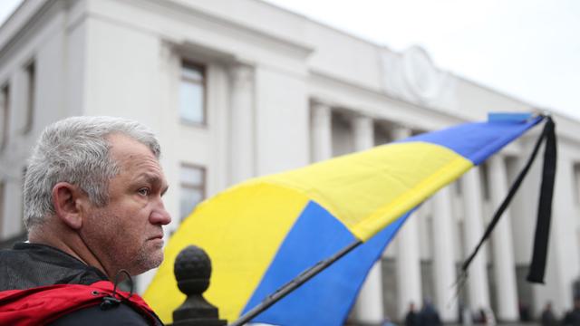 Ein Mann mit einer Ukraine-Flagge wartet vor dem Parlament in Kiew.