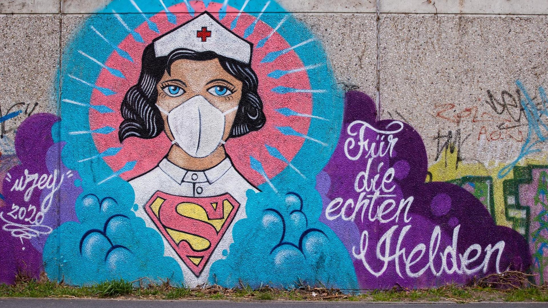 Ein Graffitti des Künstlers Kai 'Uzey' Wohlgemuth zeigt eine Krankenschwester als Superwomanan einer grauen Wand in Hamm. Dazu steht "Für die echten Helden".