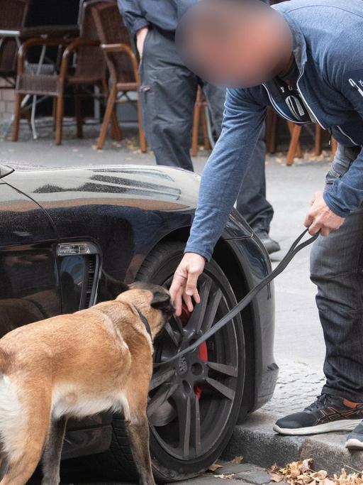 Ein Polizist untersucht mit einem Spürhund ein verdächtiges Fahrzeug. Am Montag wurde eine Razzia gegen kriminelle Mitglieder arabischer Großfamilien in Berlin durchgeführt.