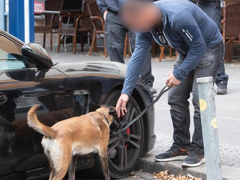 Ein Polizist untersucht mit einem Spürhund ein verdächtiges Fahrzeug. Am Montag wurde eine Razzia gegen kriminelle Mitglieder arabischer Großfamilien in Berlin durchgeführt.