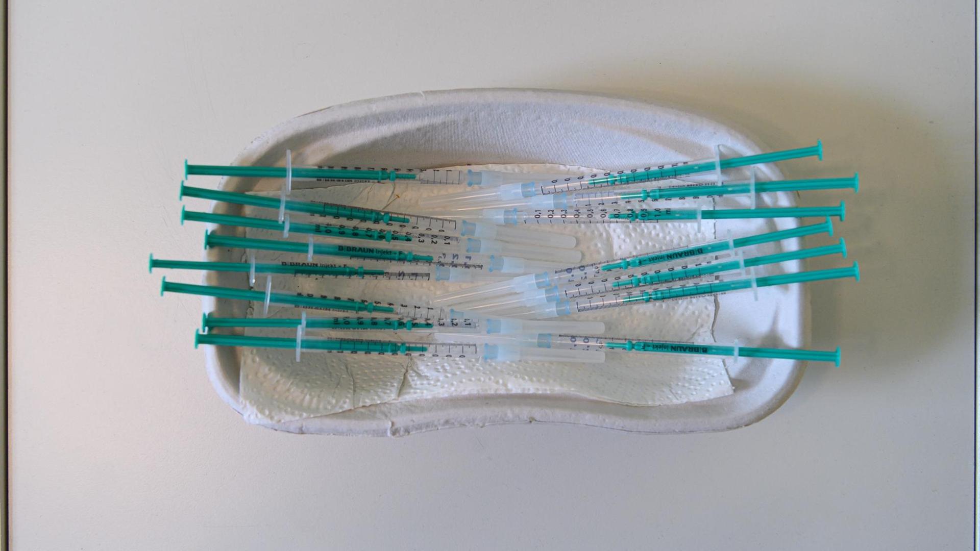Spritzen mit dem Wirkstoff Comirnaty von Biontech/Pfizer gegen das Coronavirus liegen in einer Hausarztpraxis in einer Schale auf einem Tisch. Spritzen mit dem Wirkstoff Comirnaty von Biontech/Pfizer gegen das Coronavirus liegen in einer Hausarztpraxis in einer Schale auf einem Tisch.