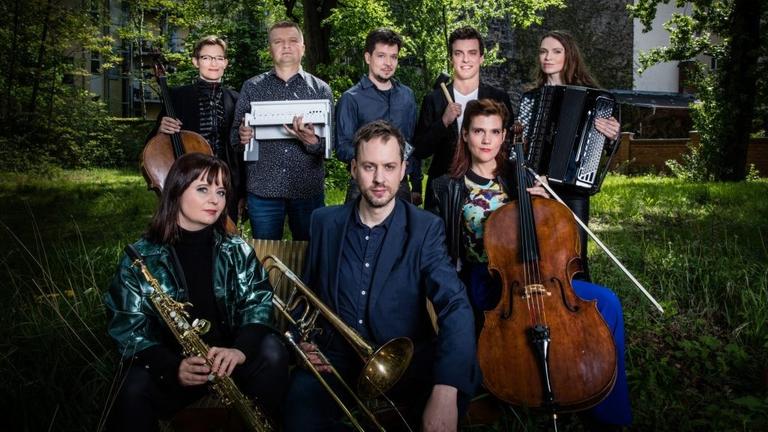 Das Ensemble steht mit seinen Instrumenten in einem begrünten Innenhof. Das Ensemble steht mit seinen Instrumenten in einem begrünten Innenhof.