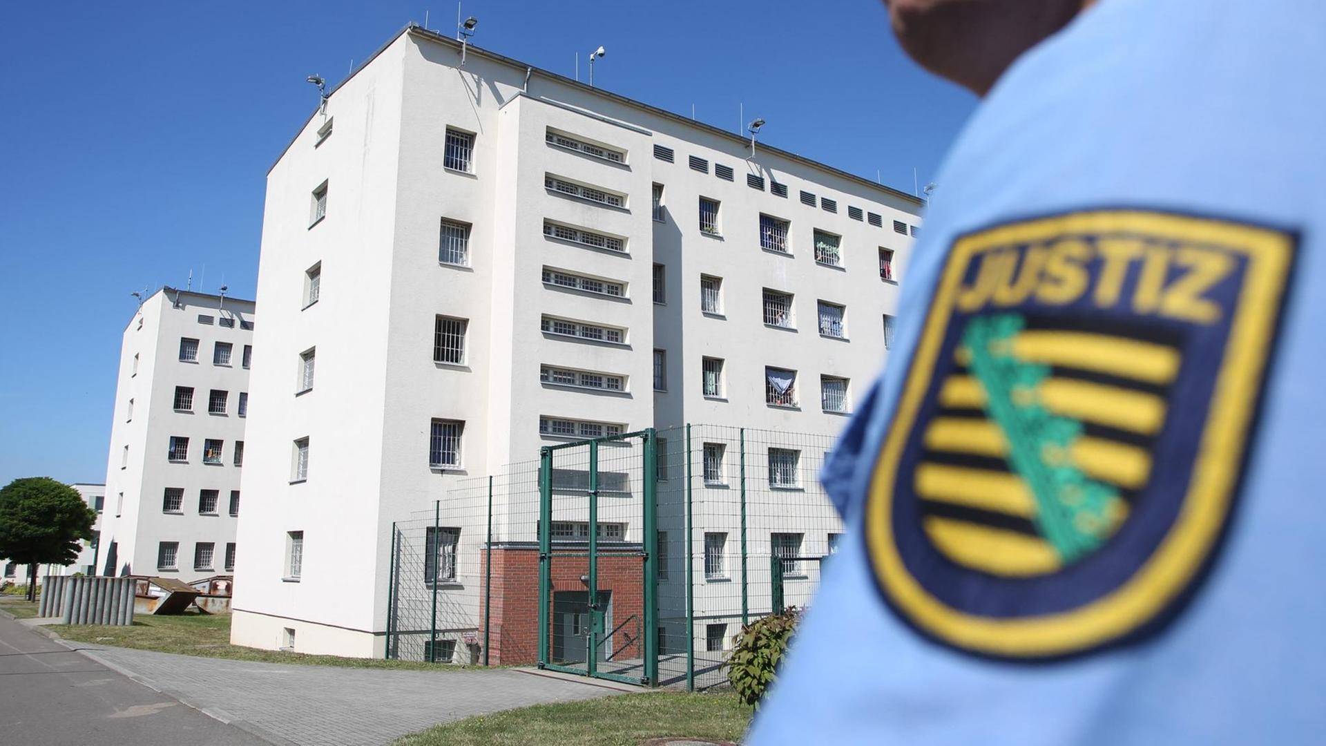 Ein sächsischer Justizbediensteter mit der Justizvollzugsanstalt Leipzig im Hintergrund. Ein sächsischer Justizbediensteter mit der Justizvollzugsanstalt Leipzig im Hintergrund.