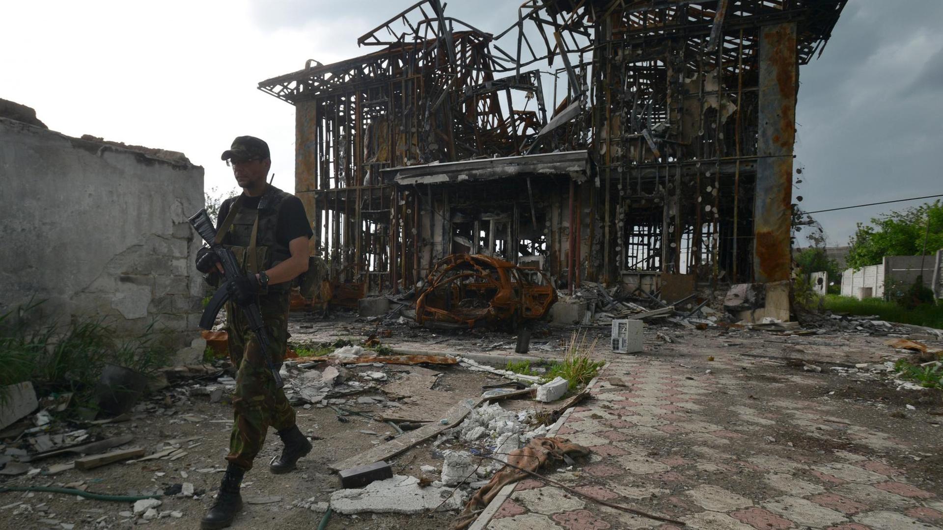 Ein ukrainischer Milizionär patroulliert vor der Ruine eines Hauses in der Nähe der Front im Osten der Ukraine Ein ukrainischer Milizionär patroulliert vor der Ruine eines Hauses in der Nähe der Front im Osten der Ukraine