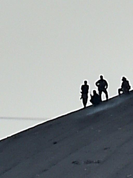 Mutmaßliche Kämpfer des Islamischen Staates hissen die Flagge der Miliz auf einem Hügel bei Kobane in Syrien.