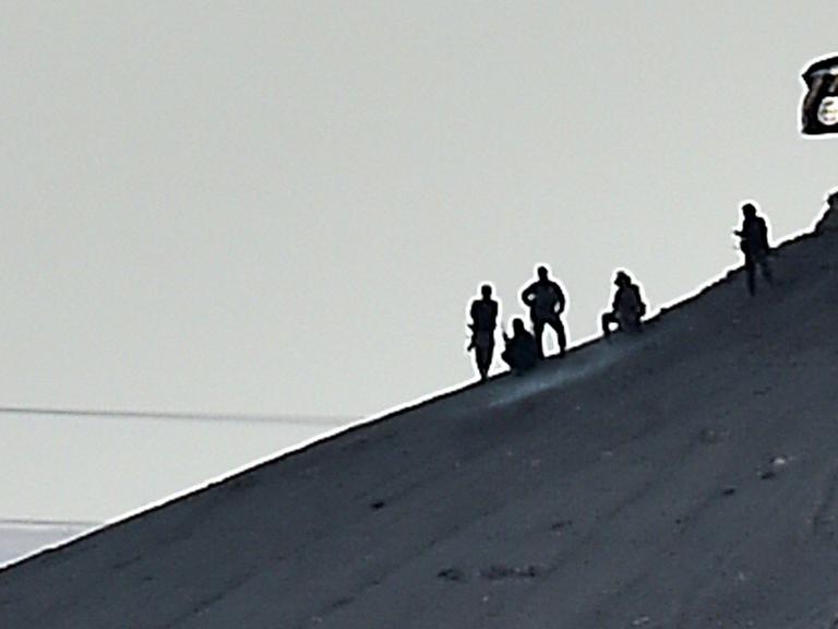 Mutmaßliche Kämpfer des Islamischen Staates hissen die Flagge der Miliz auf einem Hügel bei Kobane in Syrien.