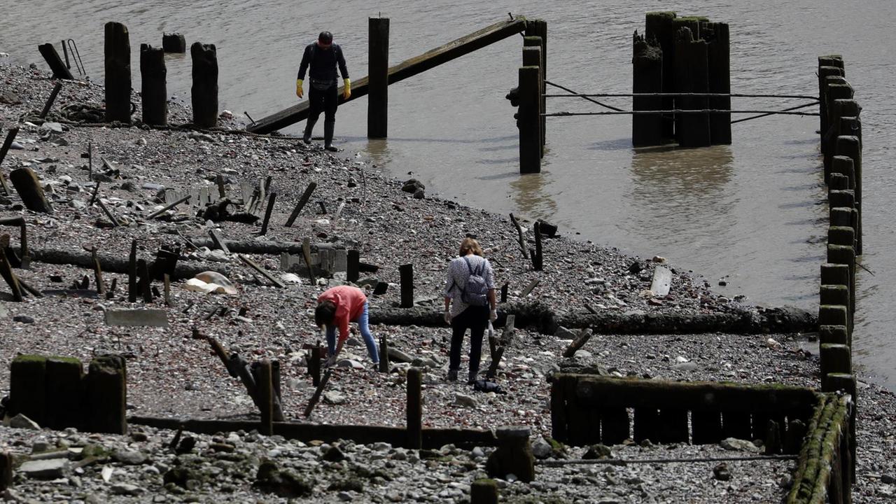 Aufnahme von mehreren Menschen, die am Ufer der Themse nach Artefakten suchen.