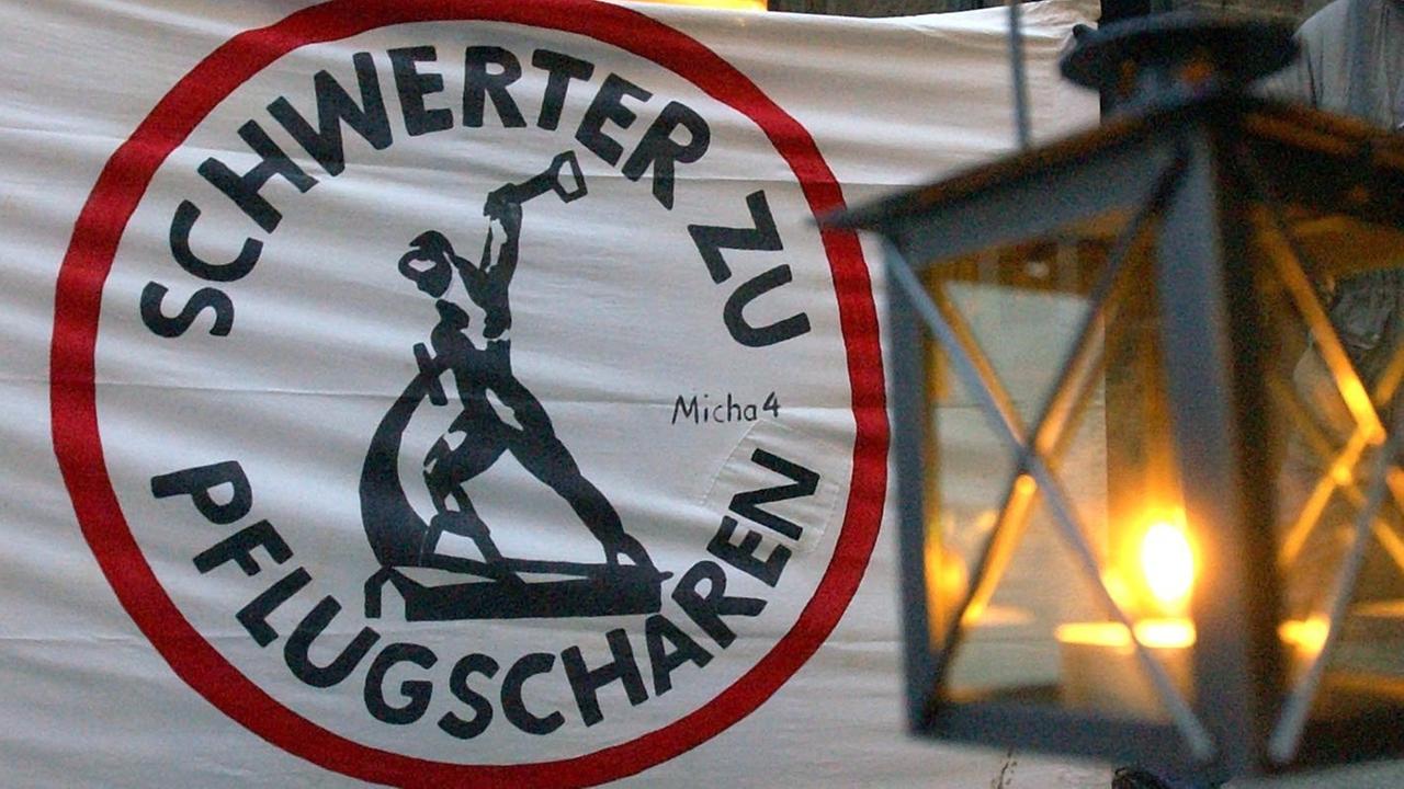 Eine Laterne hängt vor einem Transparent mit der Aufschrift "Schwerter zu Pflugscharen" in der Leipziger Innenstadt.