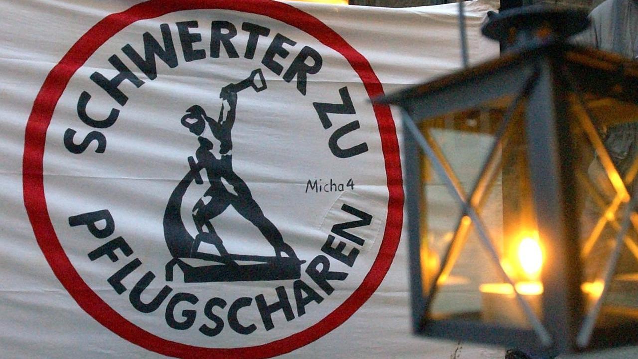 Eine Laterne hängt vor einem Transparent mit der Aufschrift "Schwerter zu Pflugscharen" in der Leipziger Innenstadt. Eine Laterne hängt vor einem Transparent mit der Aufschrift "Schwerter zu Pflugscharen" in der Leipziger Innenstadt.