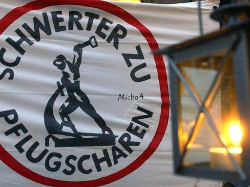 Eine Laterne hängt vor einem Transparent mit der Aufschrift "Schwerter zu Pflugscharen" in der Leipziger Innenstadt.