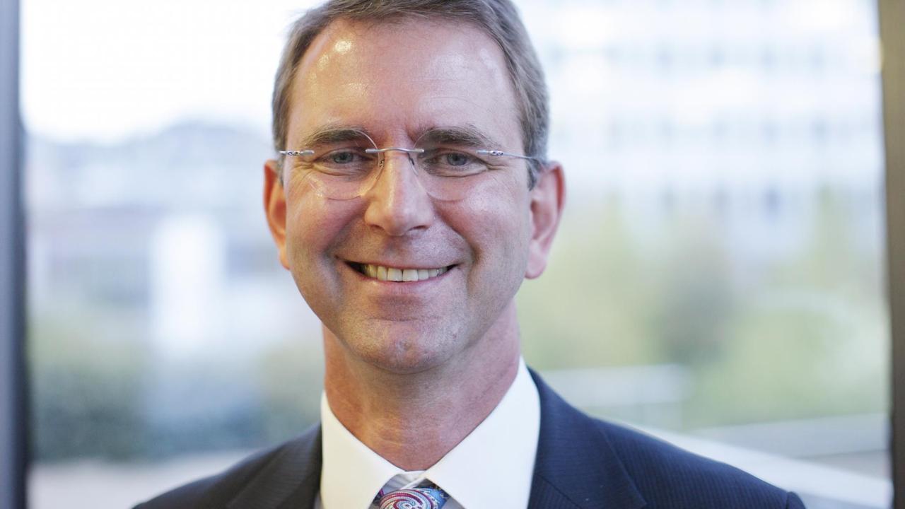 Jüngerer Mann in Anzug und Krawatte mit Brille lächelt in die Kamera Jüngerer Mann in Anzug und Krawatte mit Brille lächelt in die Kamera