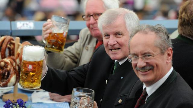 Die früheren Münchner Oberbürgermeister Hans-Jochen Vogel und Christian Ude stehen auf dem Oktoberfestes 2014 in München neben Horst Seehofer. Alle drei haben Bierkrüge in der rechten Hand und prosten in richtung Kamera.