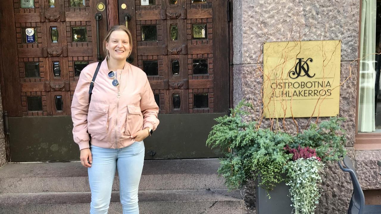 Eine junge Frau in rosa Jacke und Jeans steht auf den Treppen eines Gebäudes. Eine junge Frau in rosa Jacke und Jeans steht auf den Treppen eines Gebäudes.