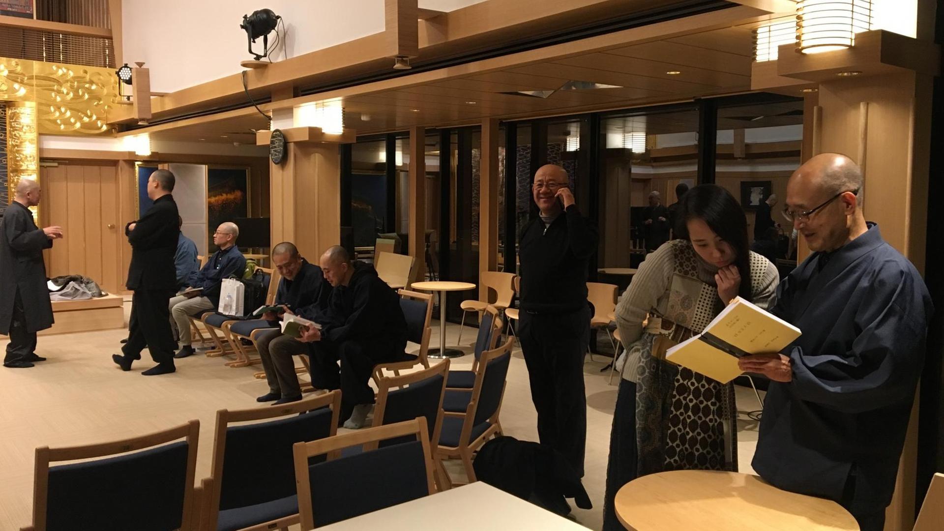 Eine Frau steht zusammen mit mehreren Männern in einem modern gestalteten Tempel in Tokio Eine Frau steht zusammen mit mehreren Männern in einem modern gestalteten Tempel in Tokio