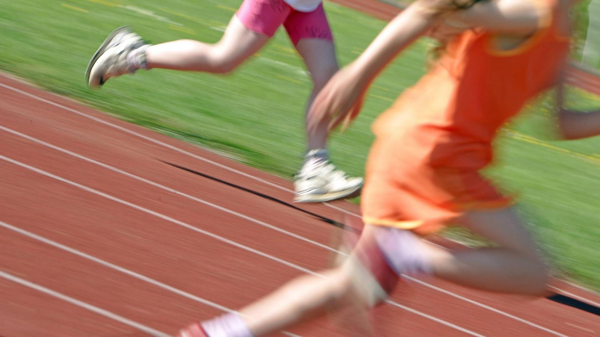 Kinder laufen über eine Laufbahn, zu sehen sind nur die Beine, unscharf. Kinder laufen über eine Laufbahn, zu sehen sind nur die Beine, unscharf.