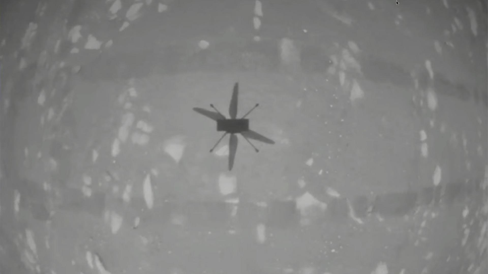 Eine schwarz-weiße Kamera-Aufnahme zeigt den Helikopter in der Luft.