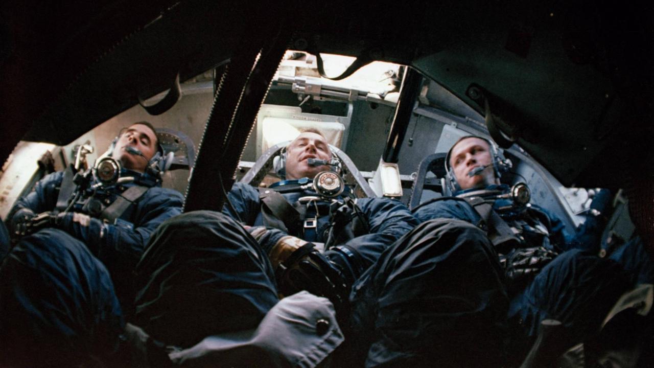 Drei Astronauten, auf dem Rücken liegend und festgeschnallt, in einer Raumkapsel Drei Astronauten, auf dem Rücken liegend und festgeschnallt, in einer Raumkapsel