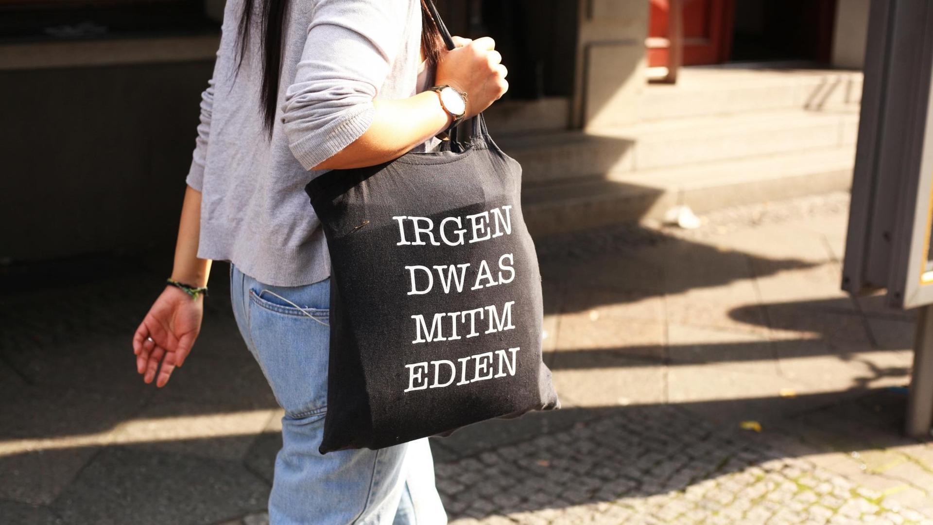 Eine junge Frau trägt am 28.09.2017 in Berlin im Stadtteil Mitte eine Jutetasche mit der Aufschrift "IRGEN DWAS MITM EDIEN" für "Irgendwas mit Medien". Eine junge Frau trägt am 28.09.2017 in Berlin im Stadtteil Mitte eine Jutetasche mit der Aufschrift "IRGEN DWAS MITM EDIEN" für "Irgendwas mit Medien".