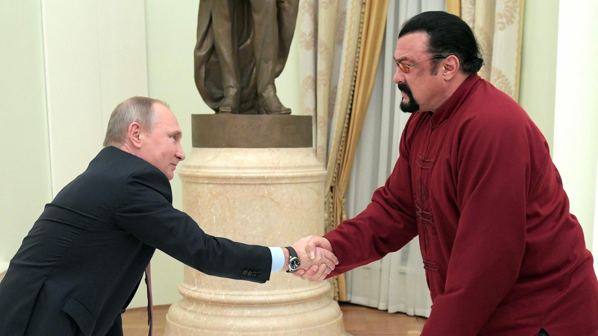 Handschlag zwischen Russlands Präsidenten Wladimir Putin (l.) und US-Schauspieler Steven Seagal im Kreml in Moskau, aufgenommen am 25. November 2016 Handschlag zwischen Russlands Präsidenten Wladimir Putin (l.) und US-Schauspieler Steven Seagal im Kreml in Moskau, aufgenommen am 25. November 2016