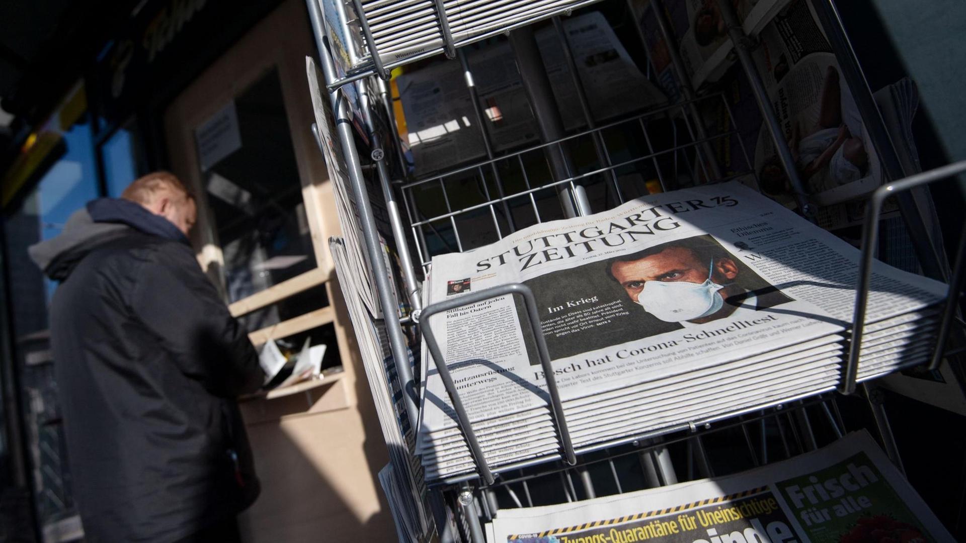 Zeitungen liegen in einem Ständer vor einem Einzelhandelsgeschäft