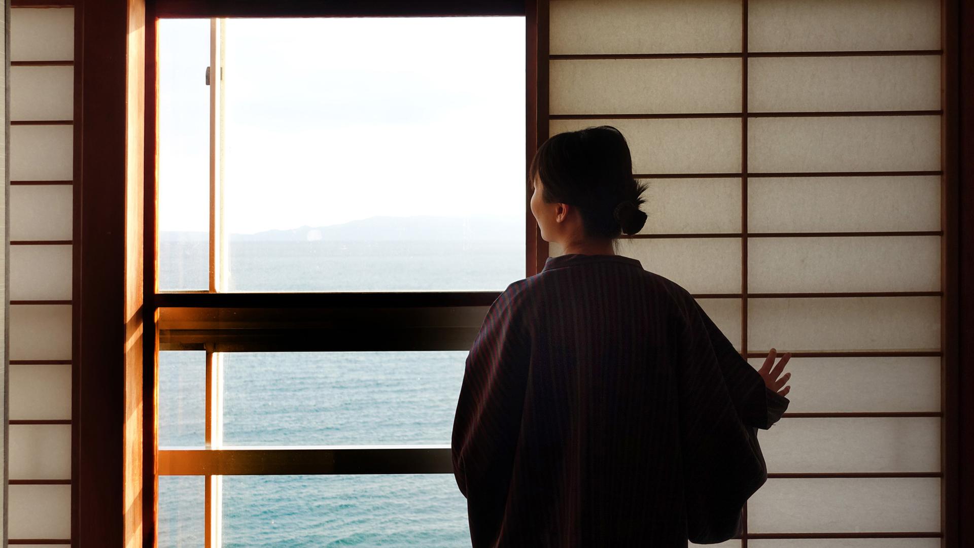 Eine Geisha schaut aus einem Teehaus auf das Meer. Eine Geisha schaut aus einem Teehaus auf das Meer.