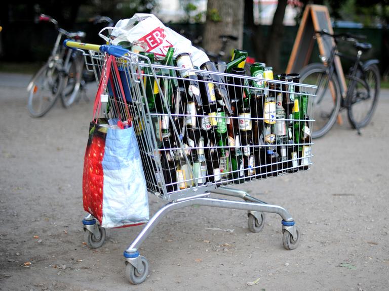 Ein Einkaufswagen mit leeren Bierflaschen steht an einer Wiese in Hannover.