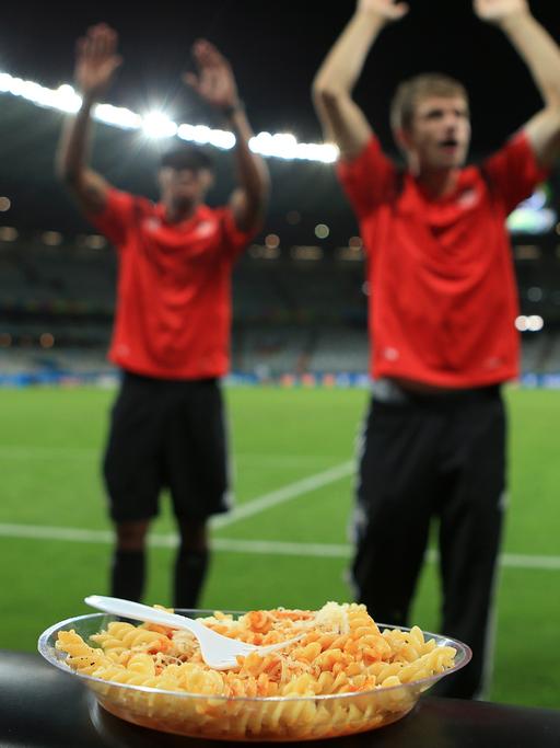 Ein Teller Nudeln steht auf der Werbeband am Rand des Fußballfelds, auf dem Spieler der deutschen Nationalmannschaft am 8. Juli 2014 das 7:1 gegen Brasilien im WM-Halbfinale feiern.