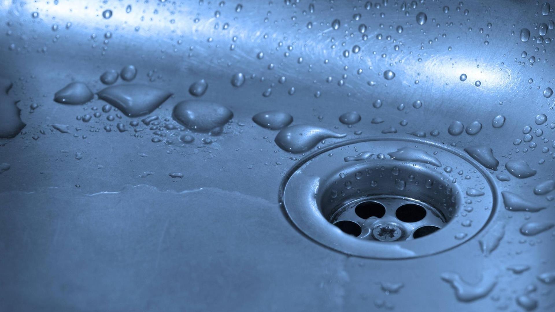 Abfluss mit Wassertropfen in einer Küchenspüle Abfluss mit Wassertropfen in einer Küchenspüle