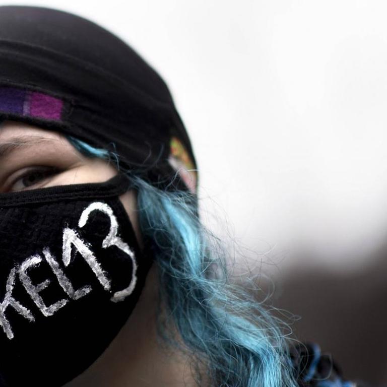 Eine junge Demonstrantin protestiert in Berlin gegen die EU-Urheberrechtsreform. Sie trägt einen Mundschutz, auf dem "Artikel 13" steht.