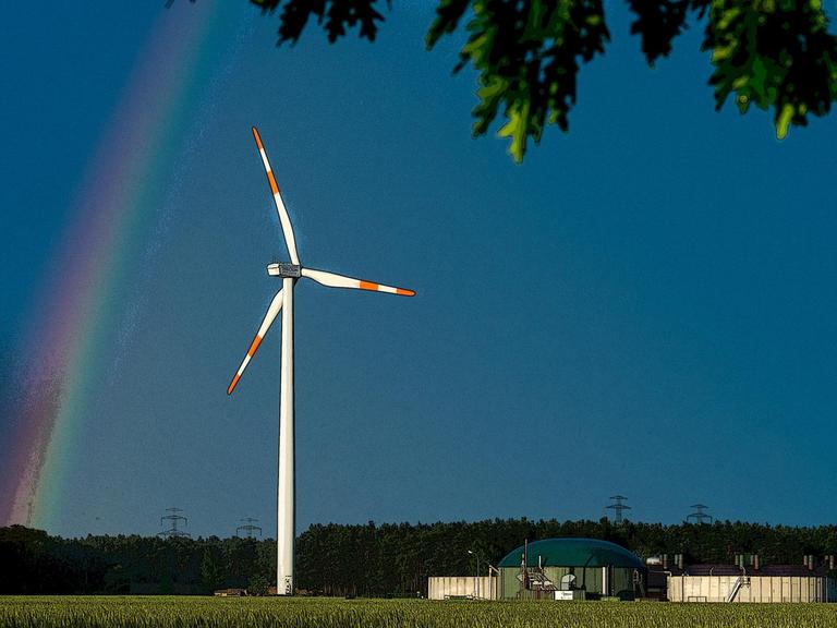 Ein Regenbogen leuchtet vor dunklen Gewitterwolken hinter einem Windrad im Landkreis Spree-Neiße nahe Peitz (Brandenburg).