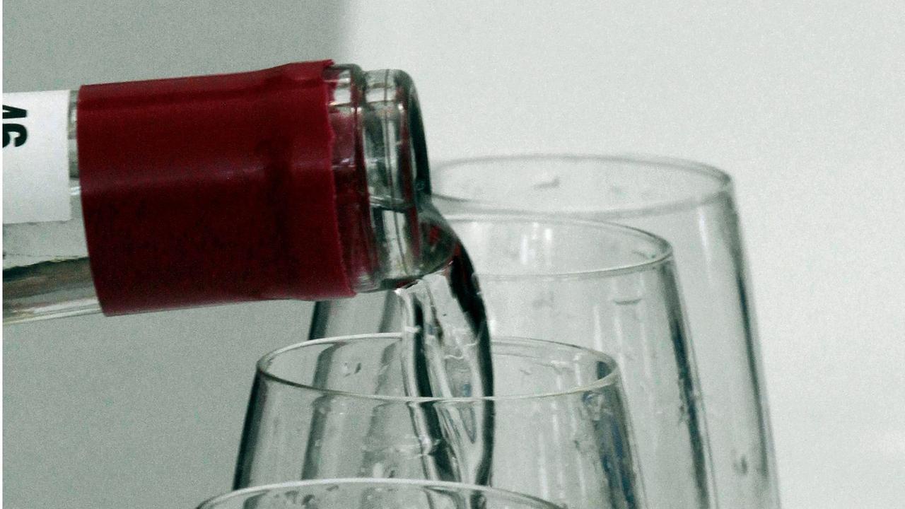 Schnaps wird von einer Flasche in mehrere Gläser gegossen. Schnaps wird von einer Flasche in mehrere Gläser gegossen.