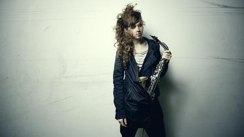 Das Bild zeigt die Jazz-Muisikerin Anna-Lena Schnabel mit einem Saxophin in der linken Hand.