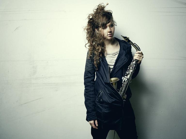 Das Bild zeigt die Jazz-Muisikerin Anna-Lena Schnabel mit einem Saxophin in der linken Hand.
