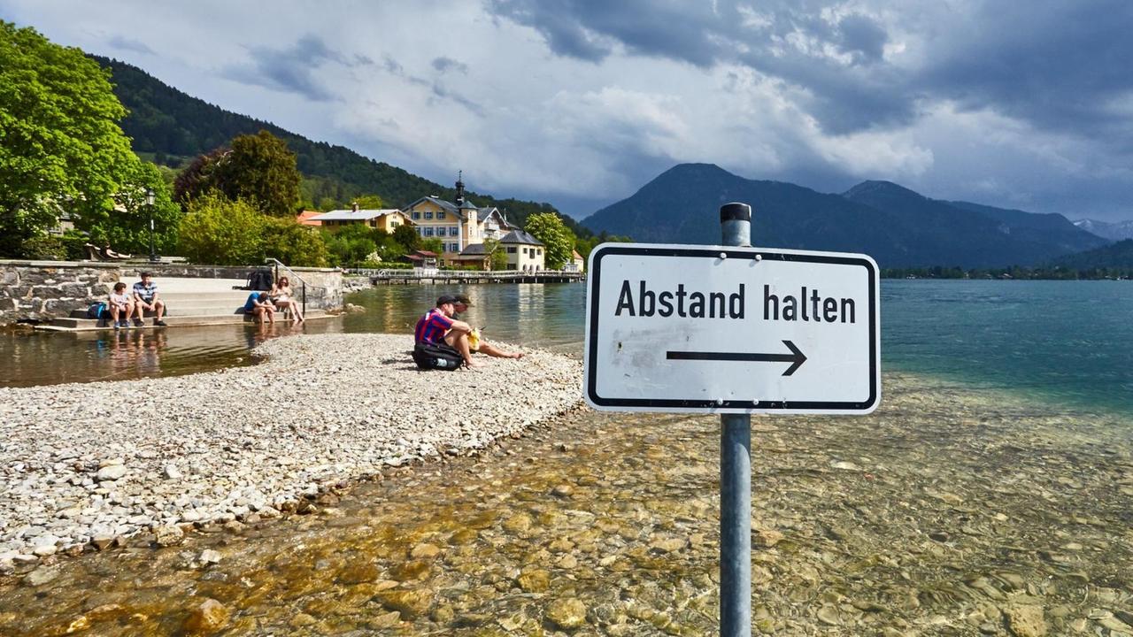 Ein Schild mit der Aufschrift "Abstand halten" an einem idyllischen See. Ein Schild mit der Aufschrift "Abstand halten" an einem idyllischen See.
