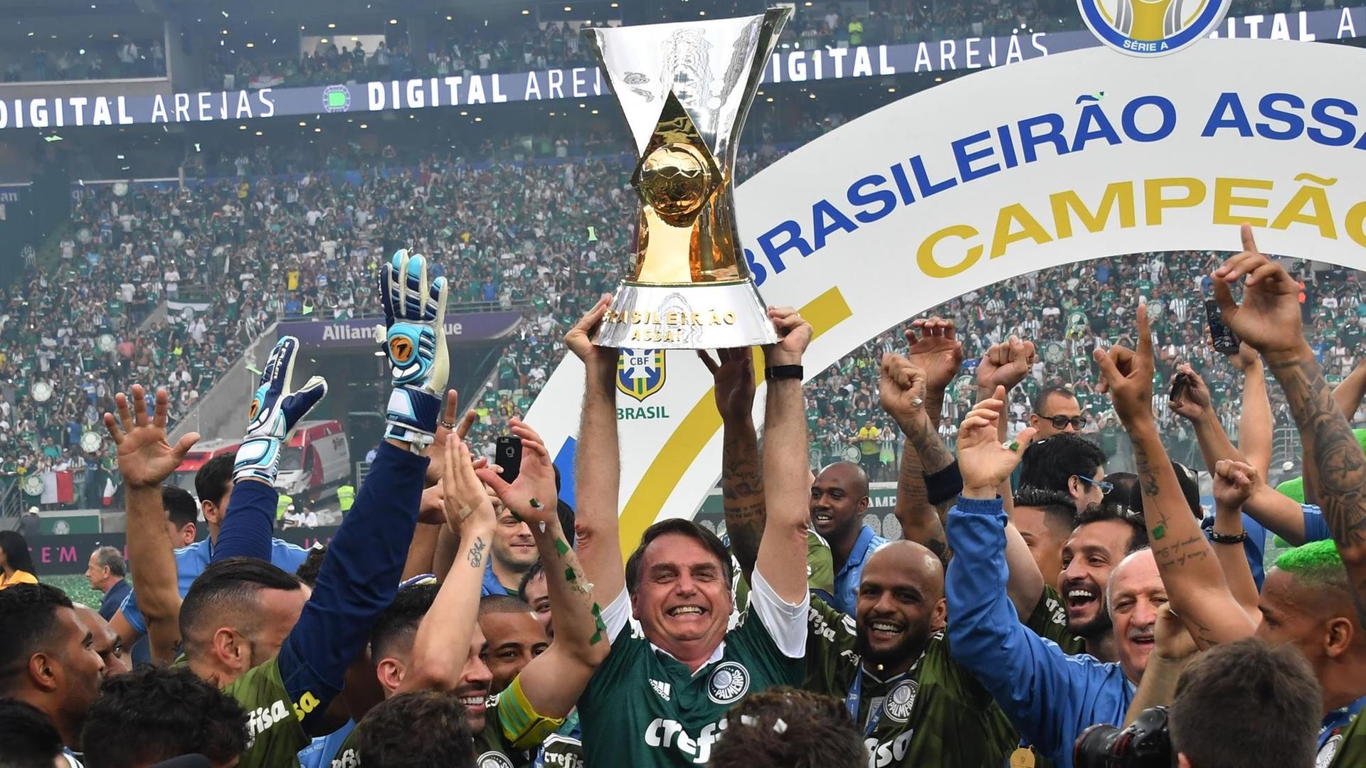 Brasiliens künftiger Präsident Jair Bolsonaro hebt den Pokal in die Luft, während er mit Palmeiras-Spieler den Titel feiert.