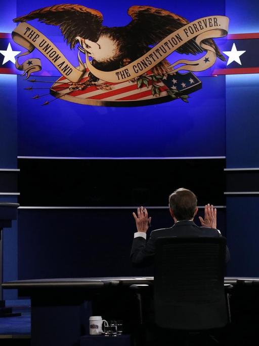 Auf der Bühne der letzten TV-Debatte stehen links der Republikaner Donald Trump und rechts Hillary Clinton. In der Mitte sitzt Moderator Chris Wallace mit dem Rücken zum Betrachter.