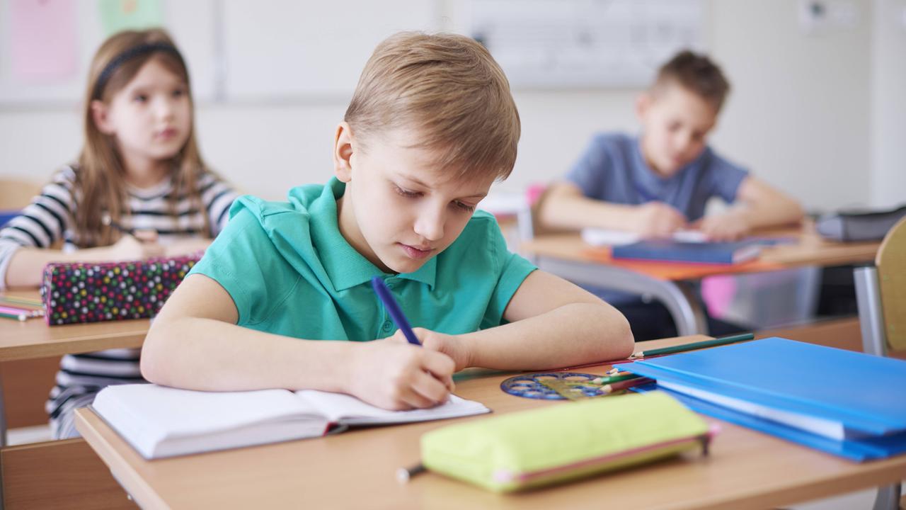 Schüler in einer Klasse, ein Schuljunge schreibt in ein Heft. Schüler in einer Klasse, ein Schuljunge schreibt in ein Heft.