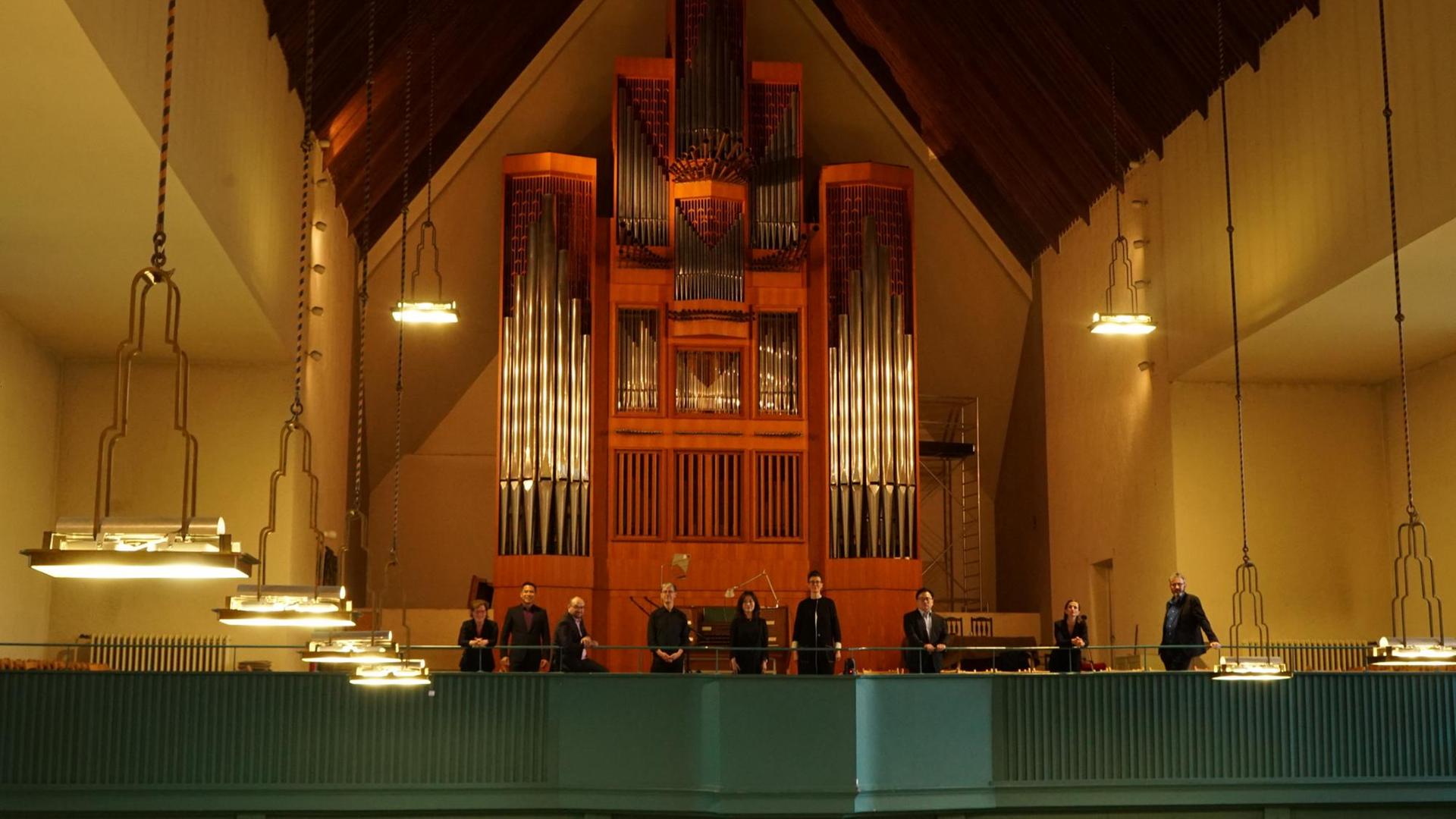 Acht Mitglieder des Chores stehen vor der Orgel in der Jesus-Christus-Kirche in Berlin-Dahlem. Acht Mitglieder des Chores stehen vor der Orgel in der Jesus-Christus-Kirche in Berlin-Dahlem.