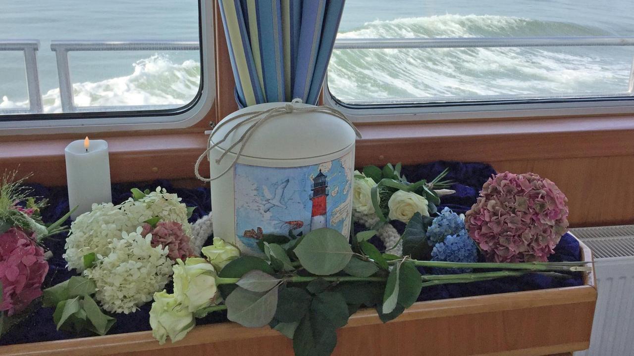 Urne und Blumen vor einem Schiffsfenster mit Blick auf das Meer. Urne und Blumen vor einem Schiffsfenster mit Blick auf das Meer.
