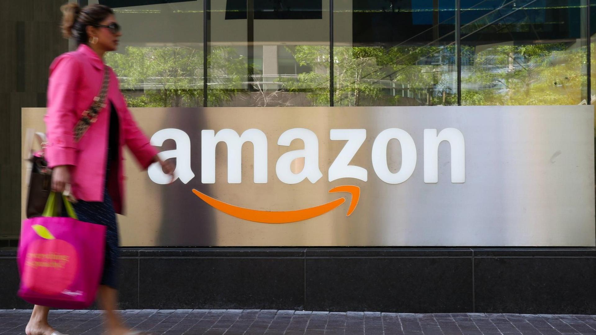 Eine Frau passiert einen Counter mit Amazon Logo in Toronto Eine Frau passiert einen Counter mit Amazon Logo in Toronto