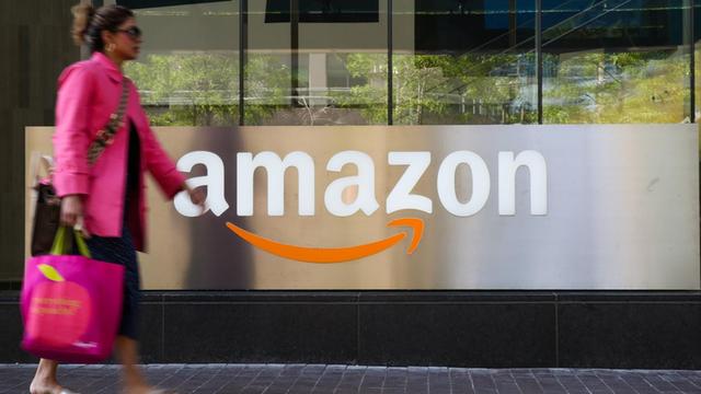 Eine Frau passiert einen Counter mit Amazon Logo in Toronto