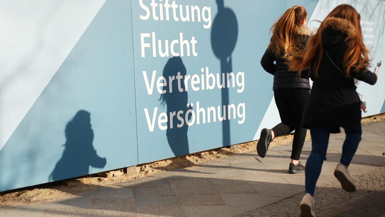 Junge Leuten rennen in Berlin am Deutschlandhaus vorbei.
