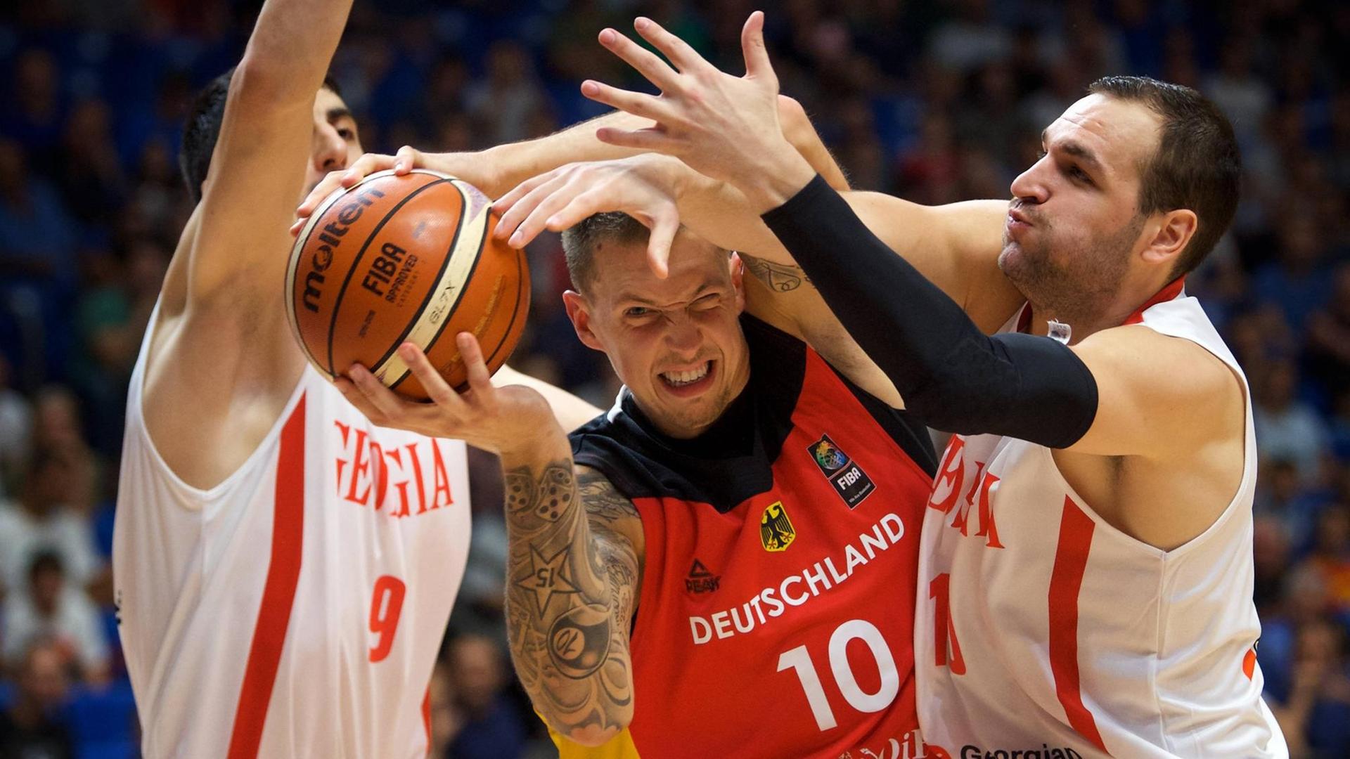 Bei der Basketball-EM in Israel setzt sich Deutschlands Daniel Theis gegen zwei georgische Spieler durch. Bei der Basketball-EM in Israel setzt sich Deutschlands Daniel Theis gegen zwei georgische Spieler durch.