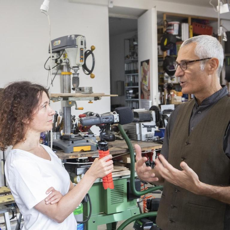 Die Autorin Aureliana Sorrento interviewt den Künstler Costantino Ciervo in dessen Wohnatelier im Prenzlauer Berg. Im Hintergrund sind große Maschinen und Werkzeug zu sehen. Die Autorin Aureliana Sorrento interviewt den Künstler Costantino Ciervo in dessen Wohnatelier im Prenzlauer Berg. Im Hintergrund sind große Maschinen und Werkzeug zu sehen.
