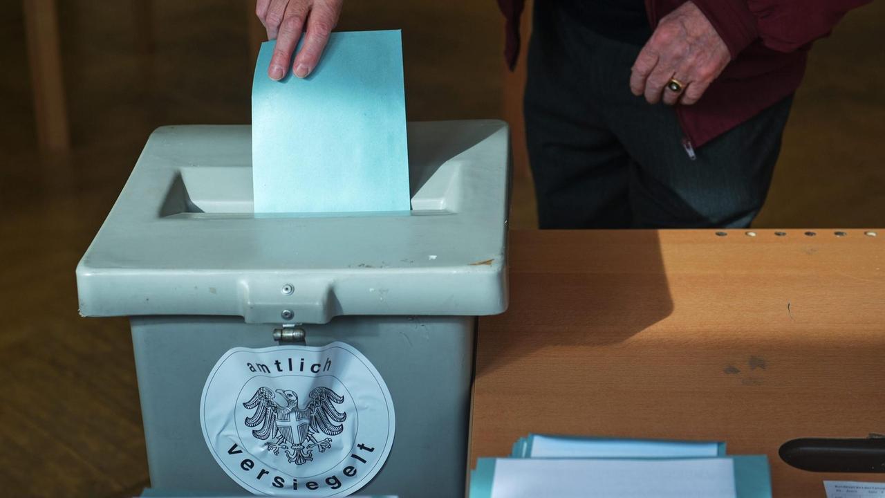 Ein Stimmzettel wird in einem Wahllokal im österreichischen Wien in eine Urne geworfen. Ein Stimmzettel wird in einem Wahllokal im österreichischen Wien in eine Urne geworfen.