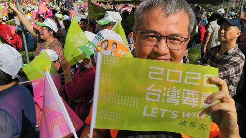 Der 55-jährige Sam hält eine grüne Fahne der DPP nach oben. Er ist Ende November 2019 auf einer Wahlkampfveranstaltung von Präsidentin Tsai Ing-wen in New Taipeh.