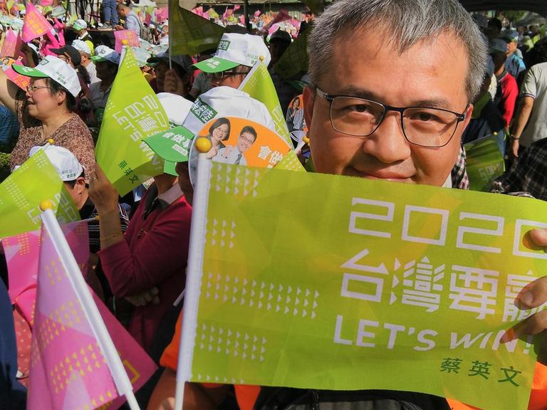 Der 55-jährige Sam hält eine grüne Fahne der DPP nach oben. Er ist Ende November 2019 auf einer Wahlkampfveranstaltung von Präsidentin Tsai Ing-wen in New Taipeh.