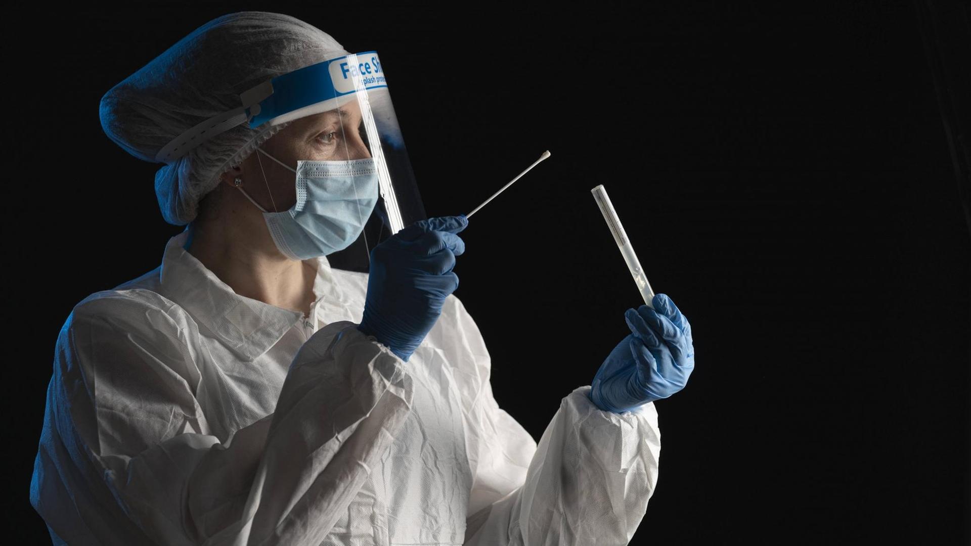 Woman in protective wear putting a swab into a tube model released Symbolfoto property released SNF00064 Woman in protective wear putting a swab into a tube model released Symbolfoto property released SNF00064