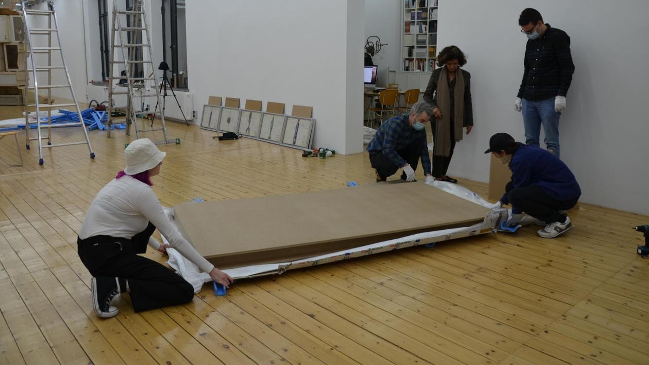 Andrée Sfeir-Semler und ihre Mitarbeitenden packen ein übergroßes Gemälde aus. Andrée Sfeir-Semler und ihre Mitarbeitenden packen ein übergroßes Gemälde aus.